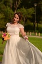 Incredibly beautiful bride with bouquet of roses. Romantic accessory of fiancee. Long haired girl in wedding gown