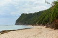 An incredibly beautiful deserted tropical beach under a cliff with clear, clean ocean water on the popular tourist island of Bali Royalty Free Stock Photo