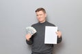 Incredulous man is holding US dollars and white blank paper sheet Royalty Free Stock Photo