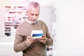 Indecisive grey-haired man reading details on a medication