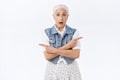 Indecisive worried old woman with grey hair, look hesitant and unsure pointing sideways, left and right with crossed