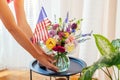 Independence day of America. Woman puts vase with flowers and Usa flag decorating home. July 4th. Memorial day Royalty Free Stock Photo