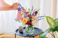 Independence day of USA. Woman puts american flag in vase with flowers decorating home. July 4th. Memorial day Royalty Free Stock Photo