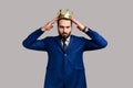 Independent bearded man wearing golden crown, looking with arrogance, confidence, privileged status.