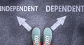 Independent and dependent as different choices in life - pictured as words Independent, dependent on a road to symbolize making