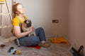 Independent single female sitting on floor and rest with pet dog in her new house during renovation, construction tools Royalty Free Stock Photo