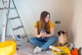 Independent single female sitting on floor and rest with pet dog in her new house during renovation, construction tools Royalty Free Stock Photo