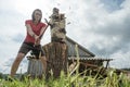 Independent woman choping wood for the winter with a large steel ax in the village, against the background of an old