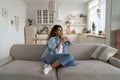 Independent woman dreaming, holding cup of coffee sits on sofa in spacious house enjoying loneliness Royalty Free Stock Photo