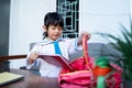 Independent young kindergarten student preparing her own stuff before going to school