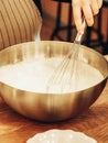 Indeterminate woman mixed batter with whisk in large metal bowl Royalty Free Stock Photo