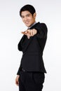 Index finger of Asian young happy confident game show mc moderator in black stylish modern formal suit standing smiling pointing