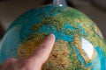 Index finger indicates Sicily on the globe, close up, blurred at the desired edges