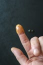 Index finger of man`s hand in yellow bee honey on black background Royalty Free Stock Photo