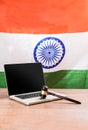 India and cyber law, laptop and wooden gavel or hammer placed over wooden table and indian tricolour or flag in the background sho