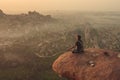 India, Hampi - December 22, 2015: A man is practicing yoga on the top of the cliff during the dawn