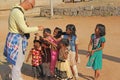 India, Hampi, 02 February 2018. A bald and cheerful European man gives gifts to Indian children. Joyful children are pulling their