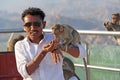 India, Hampi, January 31, 2018. Indian tourist man feeds a monkey on the hill of Anjaneya and Hanuman temple in Hampi. The monkey