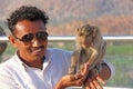 India, Hampi, January 31, 2018. Indian tourist man feeds a monkey on the hill of Anjaneya and Hanuman temple in Hampi. The monkey