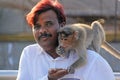 India, Hampi, January 31, 2018. Indian tourist man feeds a monkey on the hill of Anjaneya and Hanuman temple in Hampi. The monkey