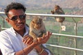 India, Hampi, January 31, 2018. Indian tourist man feeds a monkey on the hill of Anjaneya and Hanuman temple in Hampi. The monkey