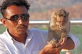 India, Hampi, January 31, 2018. Indian tourist man feeds a monkey on the hill of Anjaneya and Hanuman temple in Hampi. The monkey