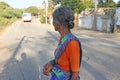 India, Hampi, January 31, 2018. An old Indian woman or an old woman in wrinkles looks at the road and bus