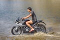 young motorcyclist rushes in the water in a spray at high speed