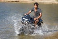 young motorcyclist rushes in the water in a spray at high speed