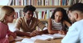 Indian and African schoolmates studying with teammates in library