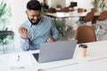 Indian asian businessman and success or victory sign with stretched hands while sitting and looking at computer screen in the Royalty Free Stock Photo