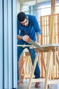 Indian Asian professional male engineer architect foreman labor worker wears safety goggles glasses and gloves using hand saw