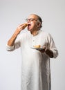 Indian asian Senior man or old man eating Samosa snack