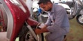 an indian automobile mechanic filling air into the tube at bike repairing service center in India