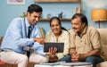Indian banker showing investment or insurance plans on digital tablet to senior couple at home - concept of financial Royalty Free Stock Photo