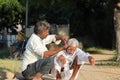 An Indian barber cuts a man`s hair in the open outdoors with the help of scissors and a comb in a native style