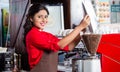 Indian barista filling coffee grinder Royalty Free Stock Photo