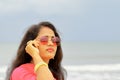 Indian beautiful woman wearing pink colored Traditional Rajasthani rajputi clothes and shiny glasses and out of focus beach