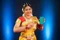 Indian bharatanatyam dancer showing green screen mobile phone by pointing finger while looking at camera - concept of