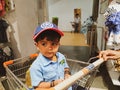 Indian Blue Shirt Wear little Kid in a Big Bazaar Sitting in a Trolley with Cap