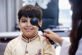 Indian boy examining eyesight checkup vision farsightedness examines ophthalmological hospital. doctor using occluder for eye