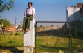 Indian boy sitting on a fence concrete support in Agra, India