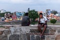 An Indian boy sitting with his phone on the ramparts of the Vellore Fort complex