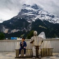 Indian boy wearing blue wind jacket enjoying icecream against snow covered mountain, Switzerland