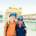 Indian boy, young sikh pilgrim stands hugging with his european friend opposite Golden Temple - main Sikh temple complex - Gurudwa Royalty Free Stock Photo
