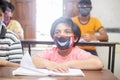 Indian boys students studying In classroom wearing mask maintaining social distancing looks at camera, school reopen during