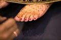 Indian bride feet coloring with indian henna paste or mehndi design of symbolic tattoos during a