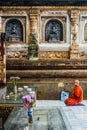 Indian Buddhist monk in meditation near The Bodhi Tree near Mahabodhi Temple while raining at Bodh Gaya, Bihar, India