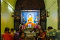 Indian Buddhist monk and people standing and praying on bare foot in front of large statue of lord Buddha inside Mahabodhi Temple. Royalty Free Stock Photo