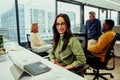 Indian business woman smiling sitting behind laptop in office while colleagues have meeting Royalty Free Stock Photo